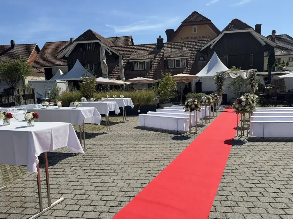 Trauplatz im Hof des Gasthof Kreuz Egerkingen mit rotem Teppich, weissen Bänken, Rosensäulen und Traubogen vor der Fassade