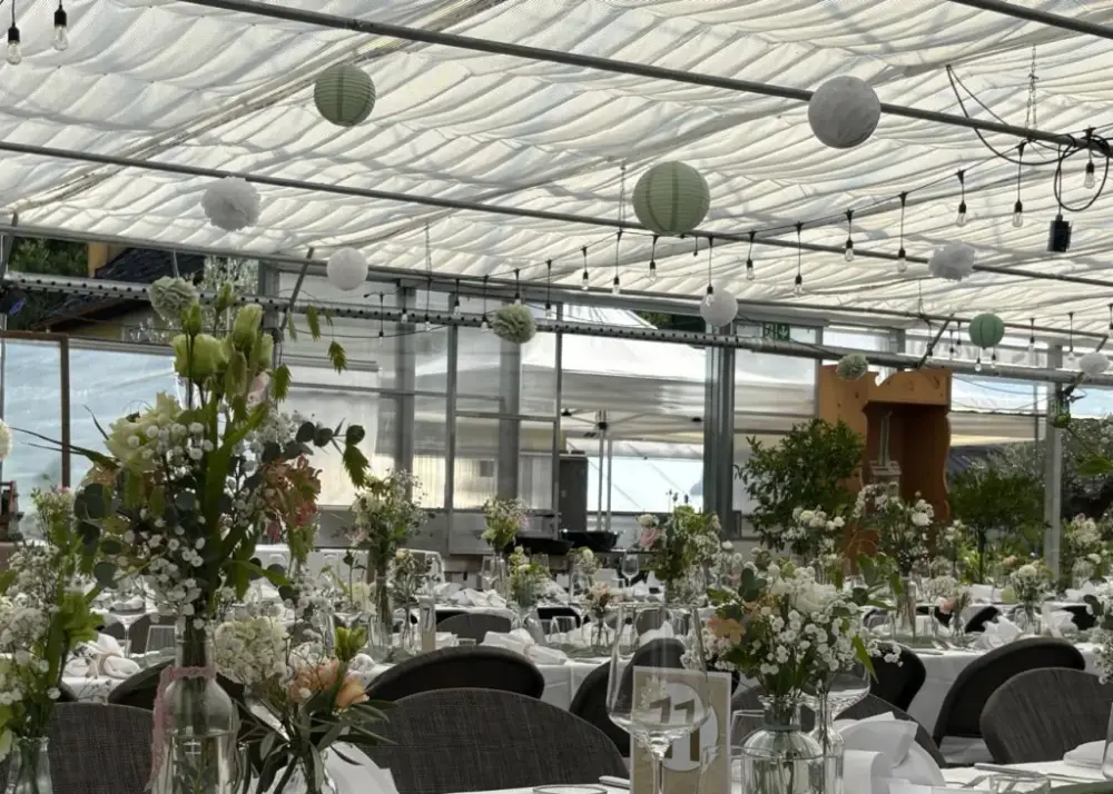 Nahaufnahme gedeckter Hochzeitstafel mit Wildblumen, Schleierkraut und Eukalyptus in Glasfläschchen, salbeigrüner Läufer und Teelichter